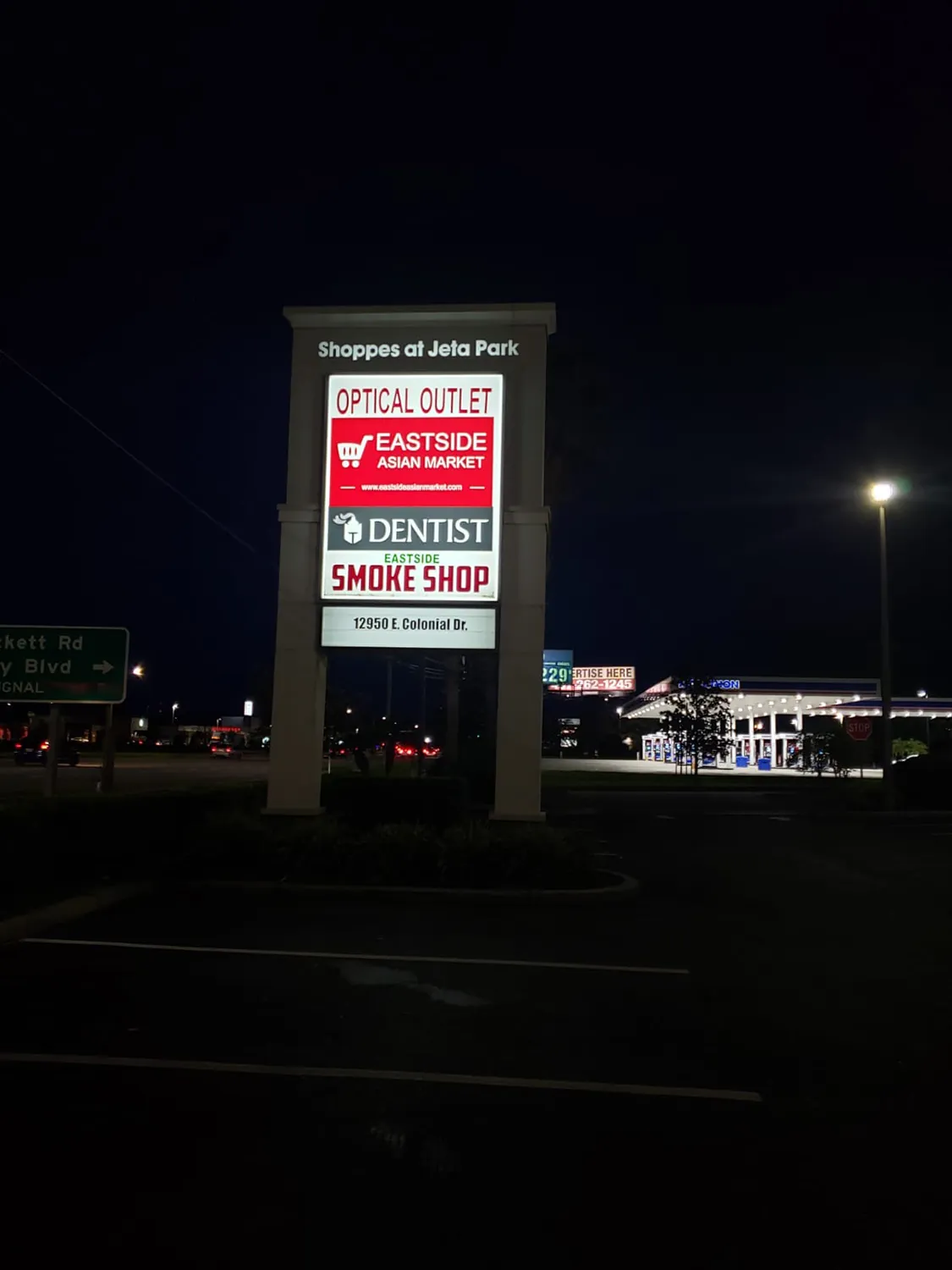 Illuminated multi-tenant shopping center pylon sign at night