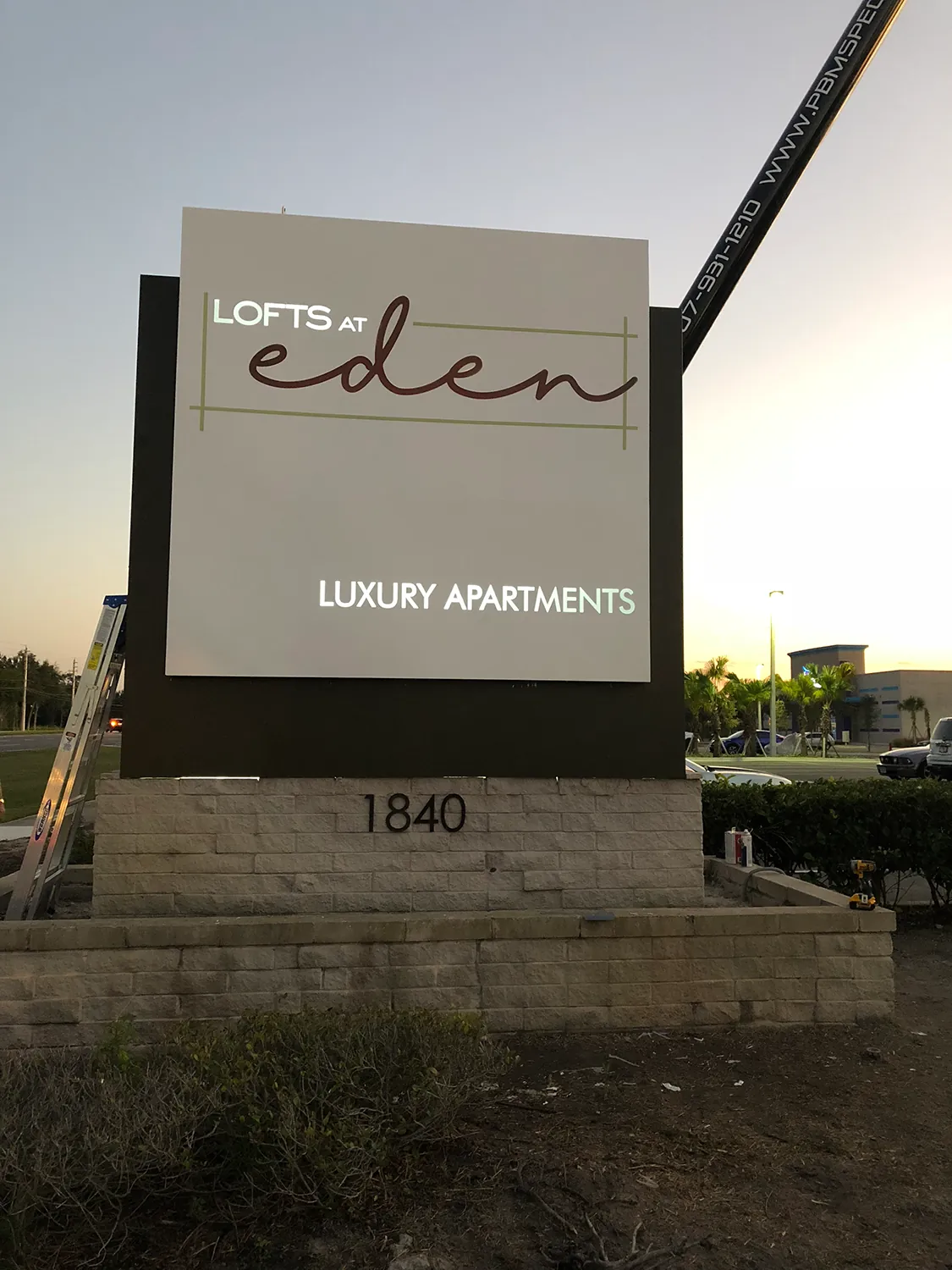 Lofts at Eden Luxury Apartments monument sign on a stone base at dusk
