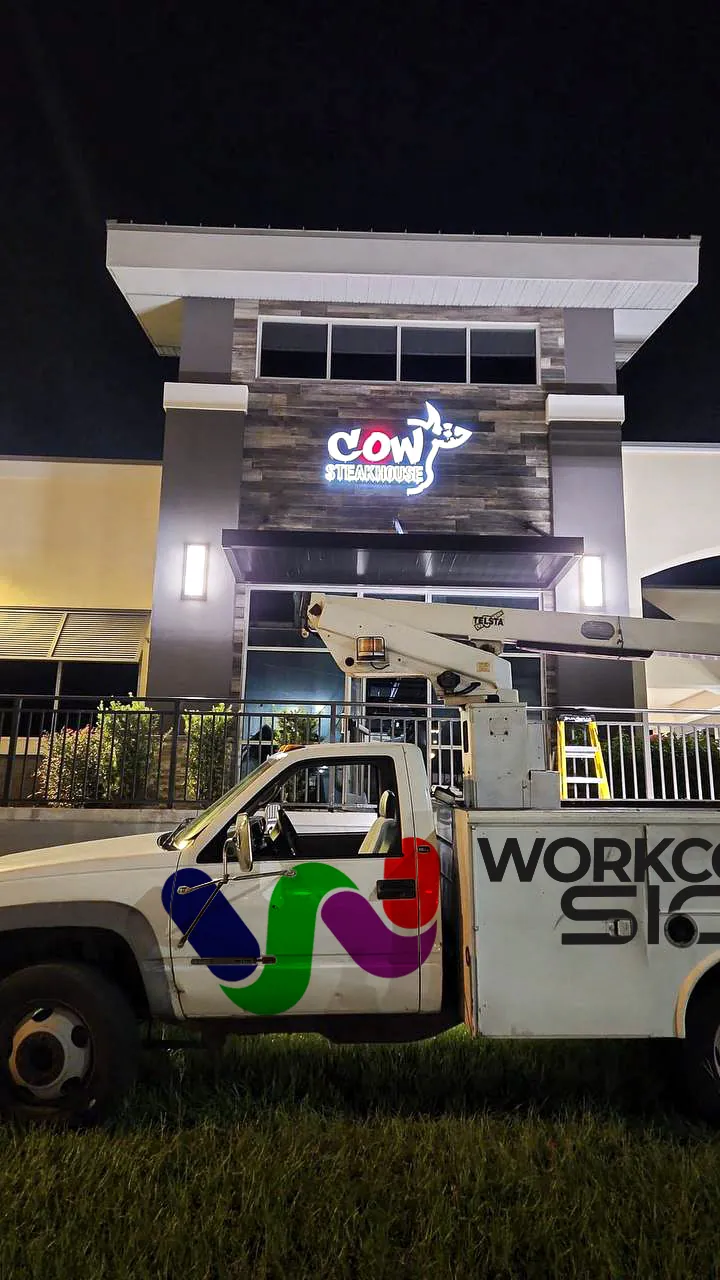 Our bucket truck parked below the newly installed Cow Steakhouse sign at night