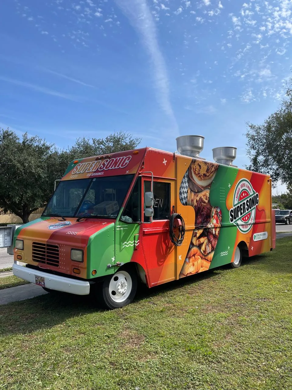 Front three-quarter view of the Super Sonic food truck wrap parked on grass