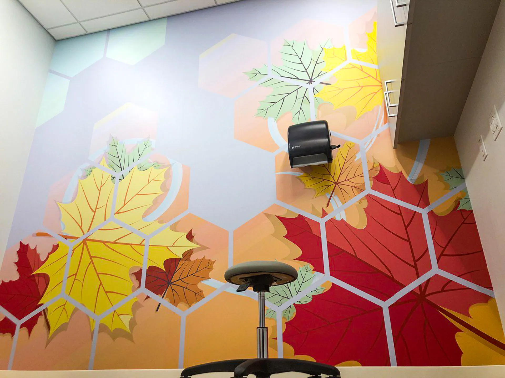 Printed wall wrap with oversized autumn maple leaves on a hexagon pattern inside an office room