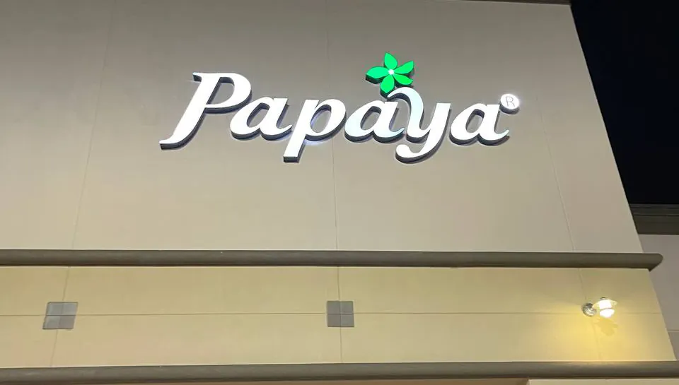 Papaya front-lit channel letters glowing white on a storefront at dusk