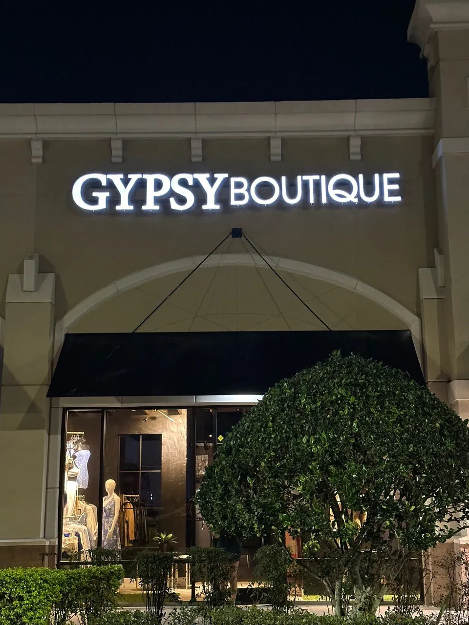 Gypsy Boutique illuminated letters on a storefront at night