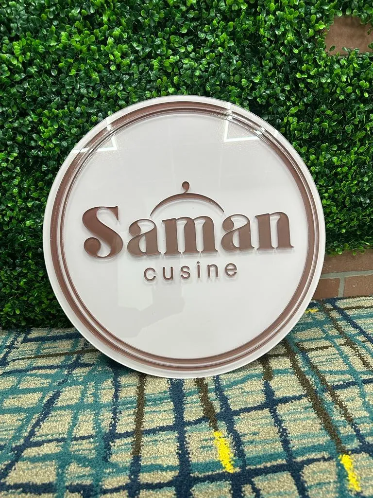 Round dimensional Saman Cuisine logo sign on a boxwood wall