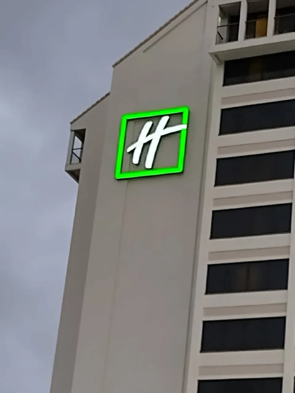 Green illuminated logo box sign on a hotel tower