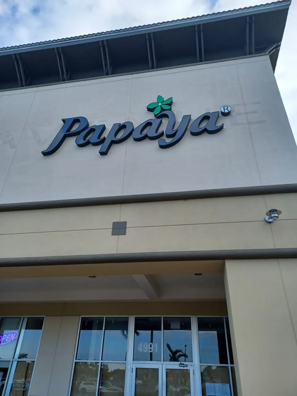 Papaya channel letters with a green flower logo on a storefront by day