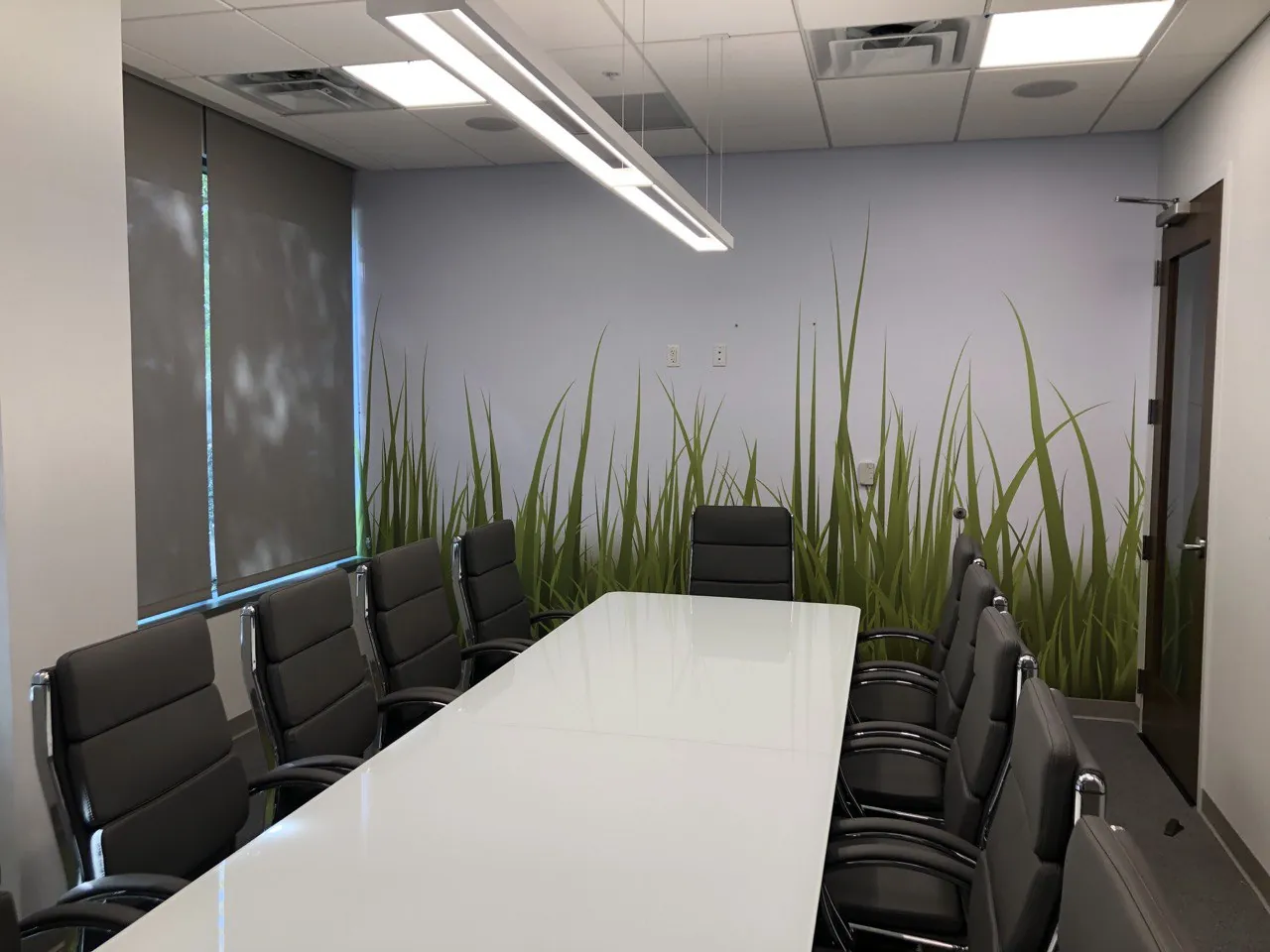 Conference room with a tall-grass wall mural behind the table