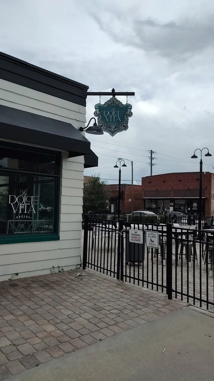 La Dolce Vita Social projecting blade sign on a storefront beside a patio