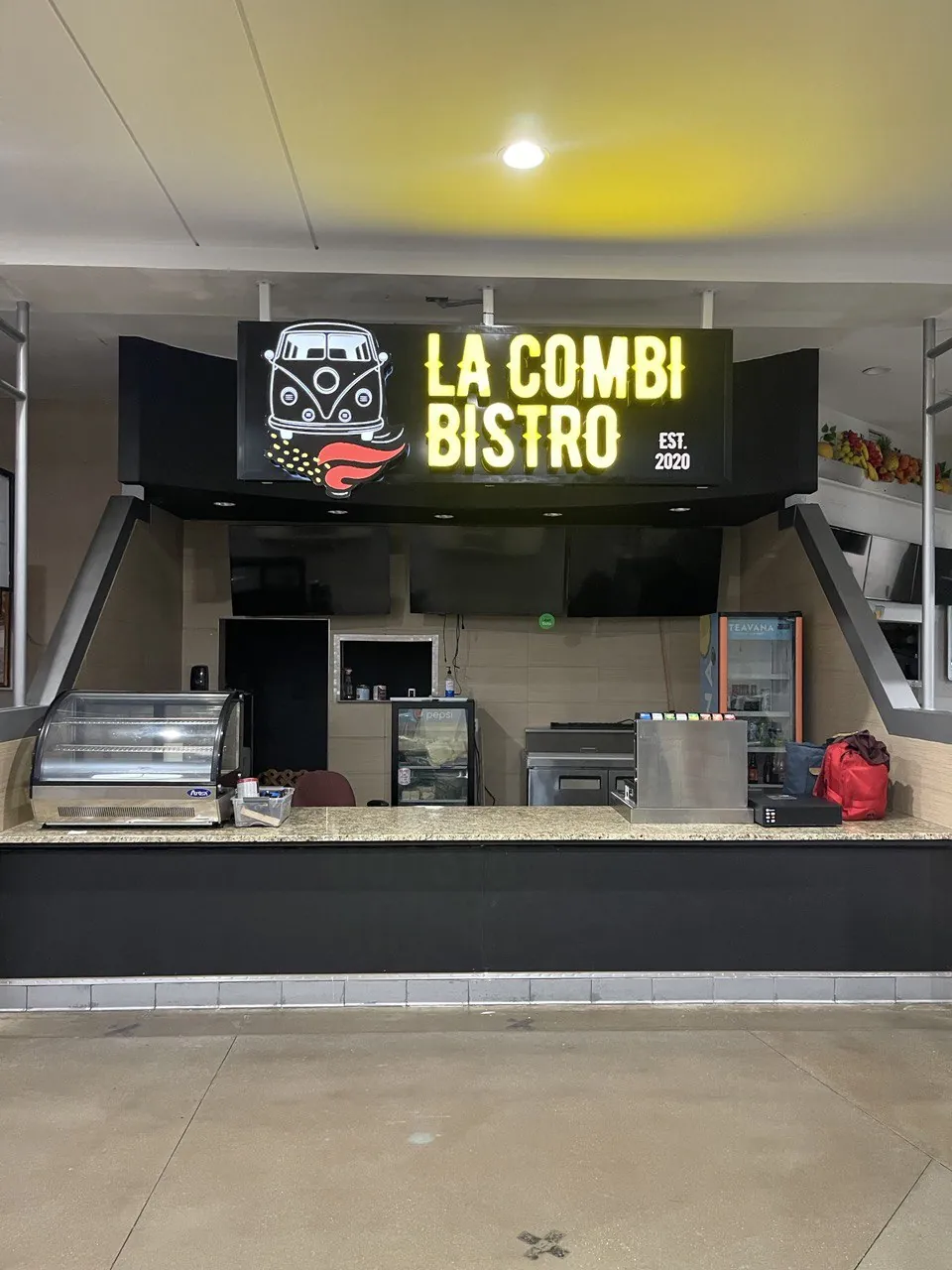 Illuminated La Combi Bistro sign above a food counter